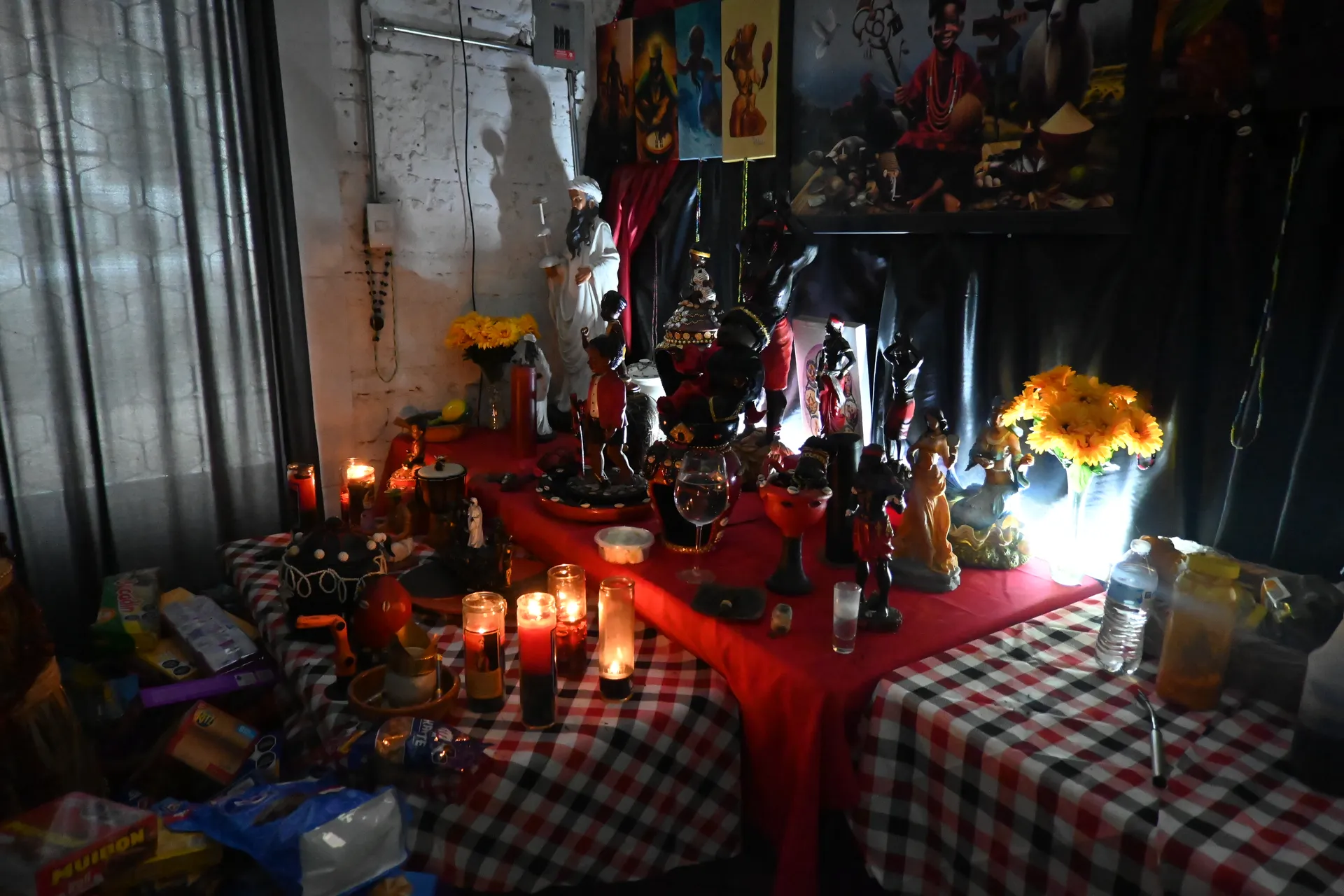 Altar de Santería con estatuas, velas, tela roja y girasoles